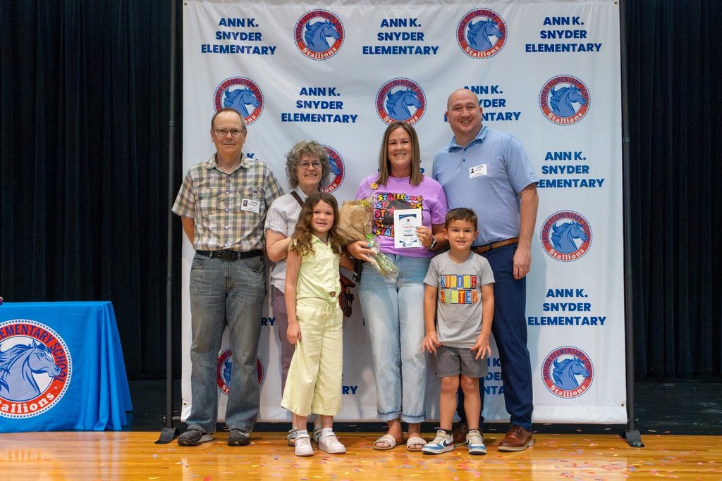 Family with staff member holding award plaque and flowers.