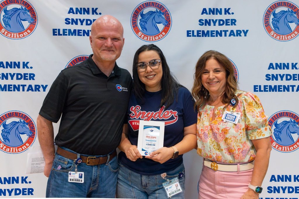 Superintendent and Board President with staff member holding award plaque.