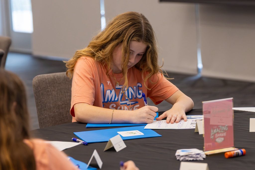 Girl takes notes sitting at a table.