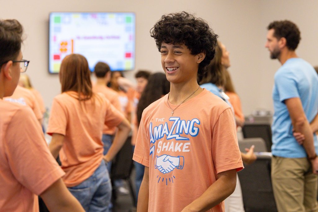 Boy smiling while talking to another student.