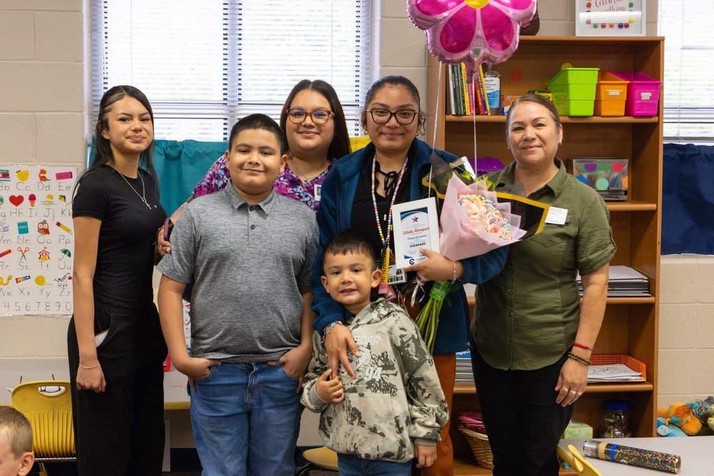 Family with staff member holding award plaque, flowers, and a balloon.