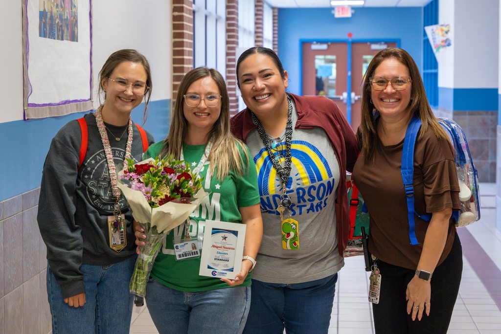 Staff members with colleague holding award plaque and flowers.