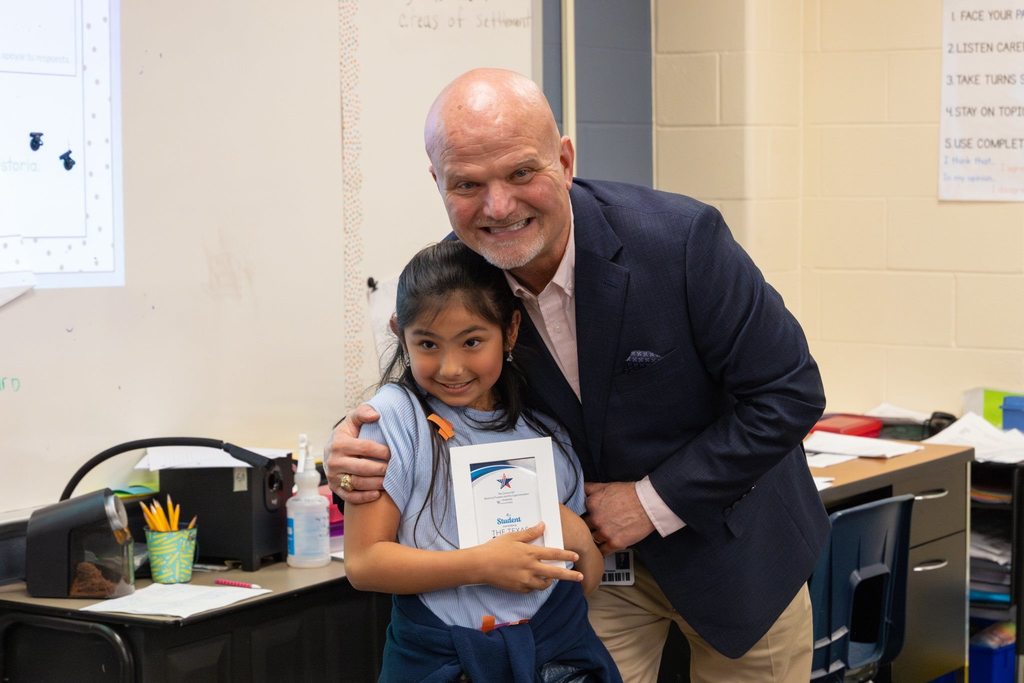 Superintendent with student  holding award plaque.