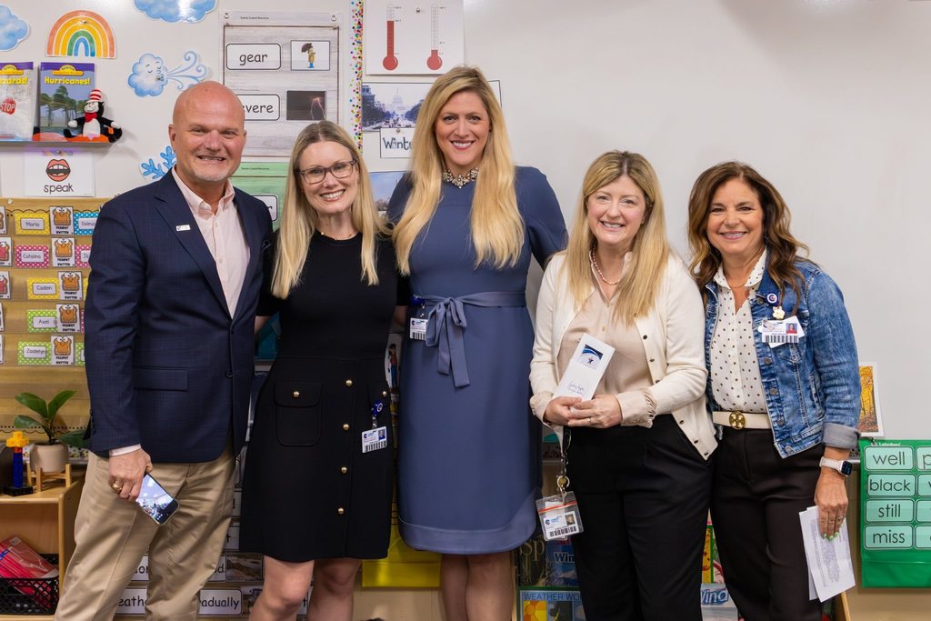 Superintendent and three board members congratulate teacher with award plaque.