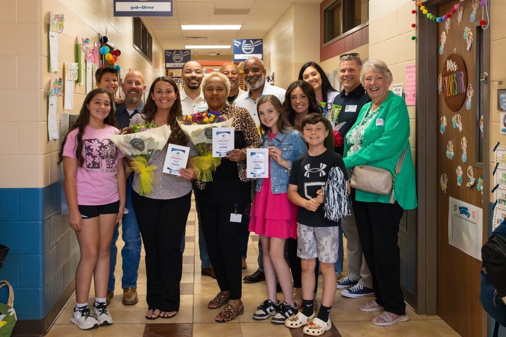 Three award winners joined by their families in school hallway.