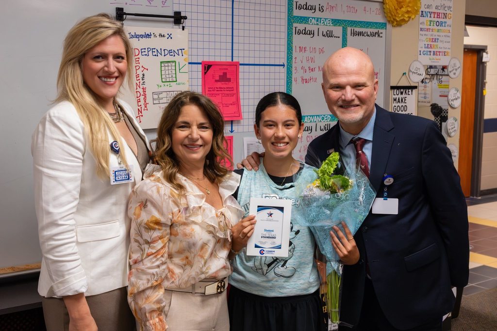 Superintendent and board members congratulate student with award plaque and flowers.