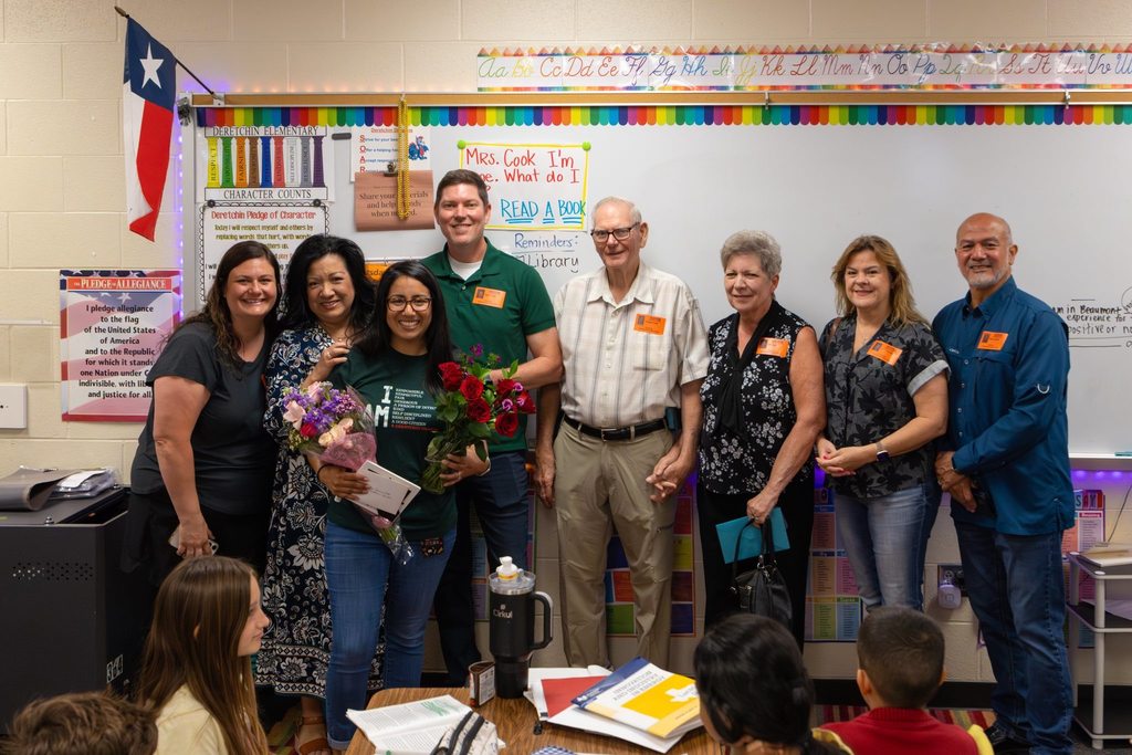 Staff member with award plaque and flowers joined by family.