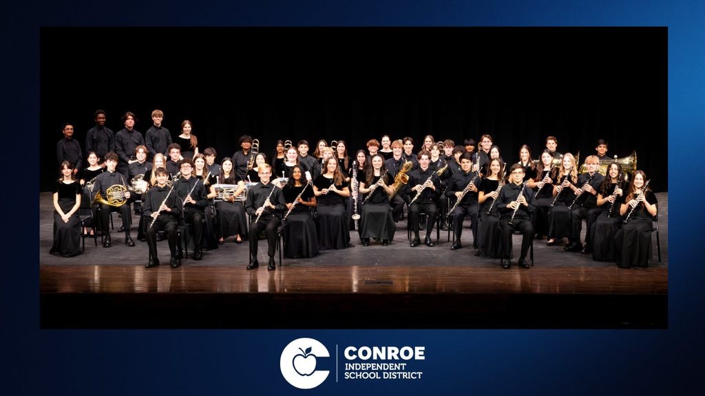 Full orchestra in black formalwear holding instruments.