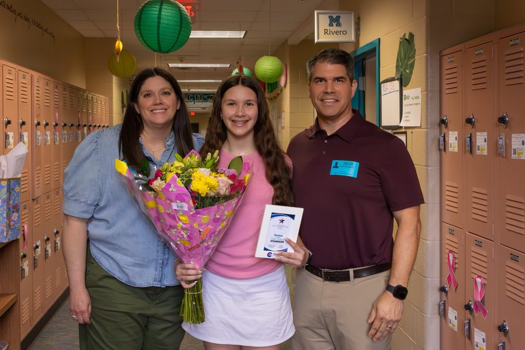 Student holds award plaque and flowers joined by family.
