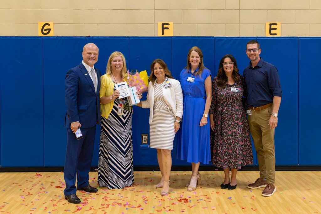 Administration presents award plaque and flowers to staff member.