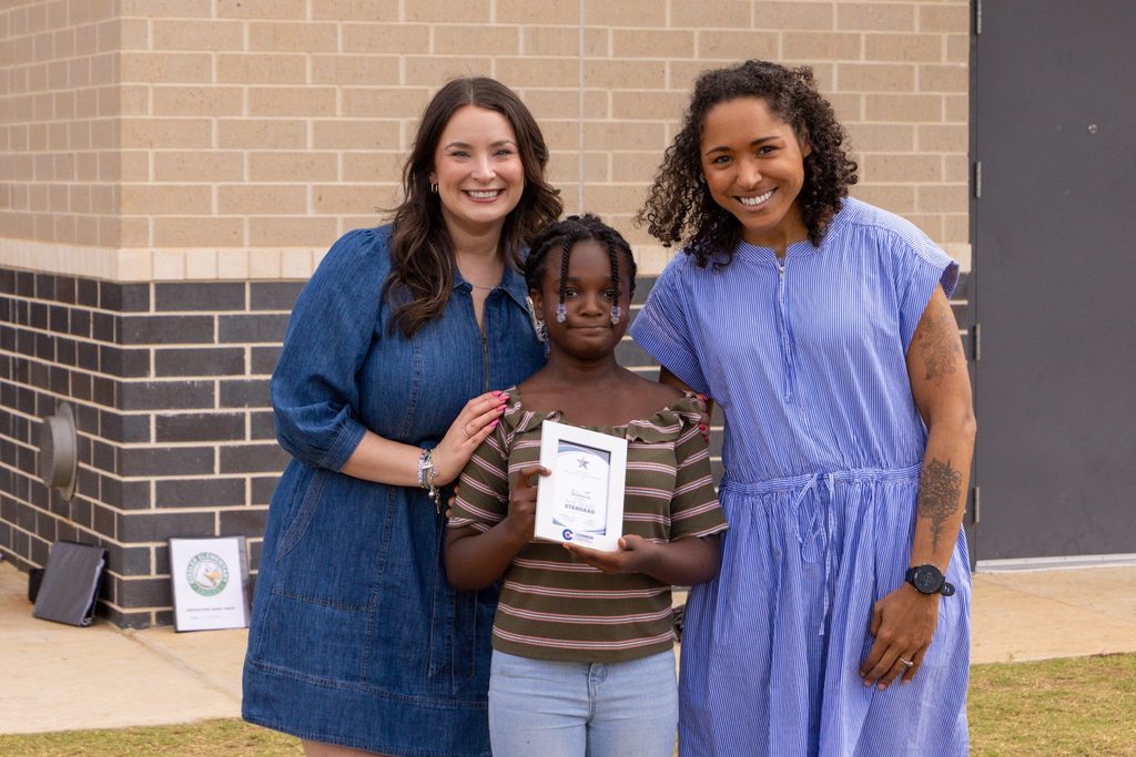Staff member and family congratulate student holding award.