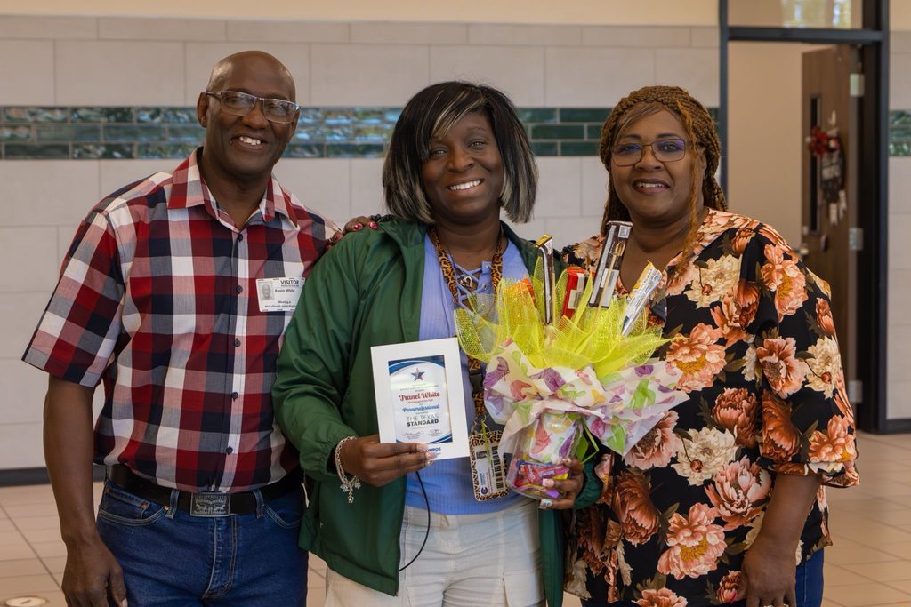 Staff member holding award plaque and candy bouquet joined by family.