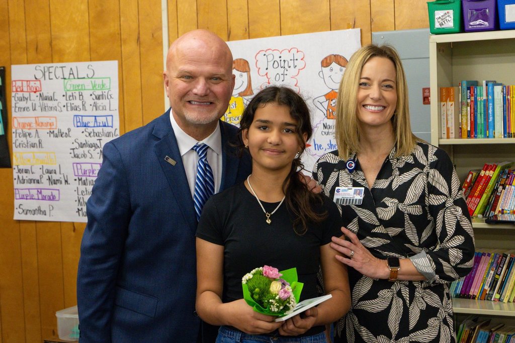 Superintendent and board member present student with award.