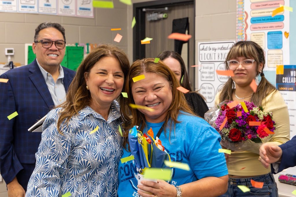 Board President hugs staff member after receiving award as confetti falls.