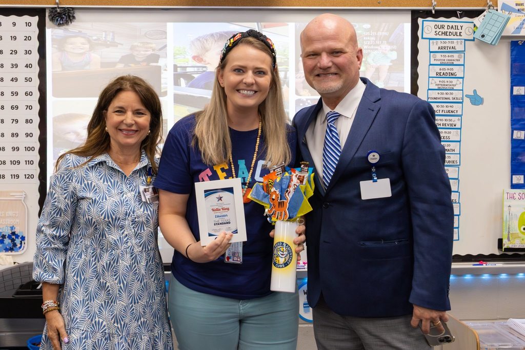 Superintendent and Board President present teacher with award plaque.