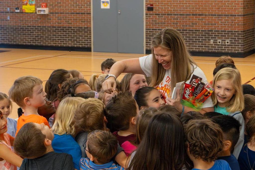 Staff member holding candy bouquet surrounded by students.