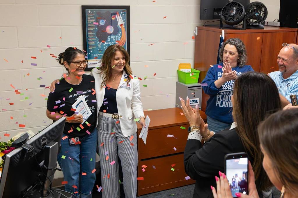 Board President congratulates staff member as confetti falls.