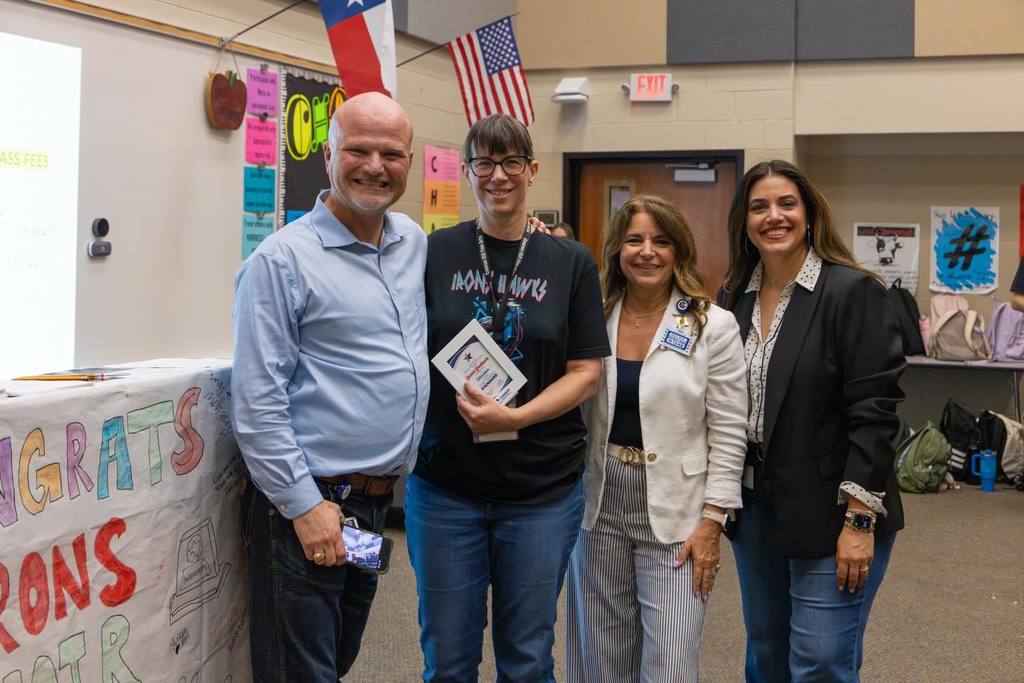 Superintendent and two staff members congratulate staff member holding award plaque.