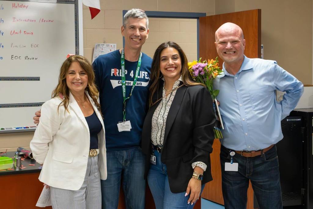 Superintendent and two board members congratulate teacher.