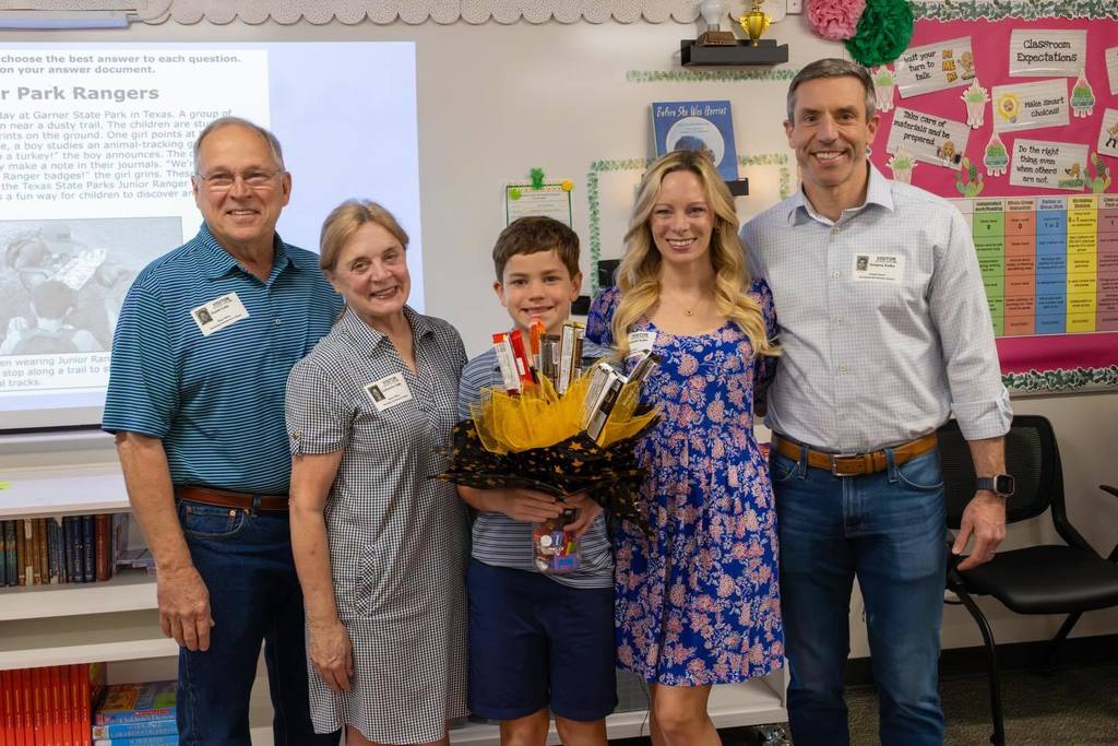 Student holding candy bouquet joined by family.