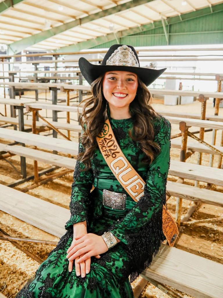 Montgomery County Fair Queen Delaney Miller sitting in rodeo arena bleachers.