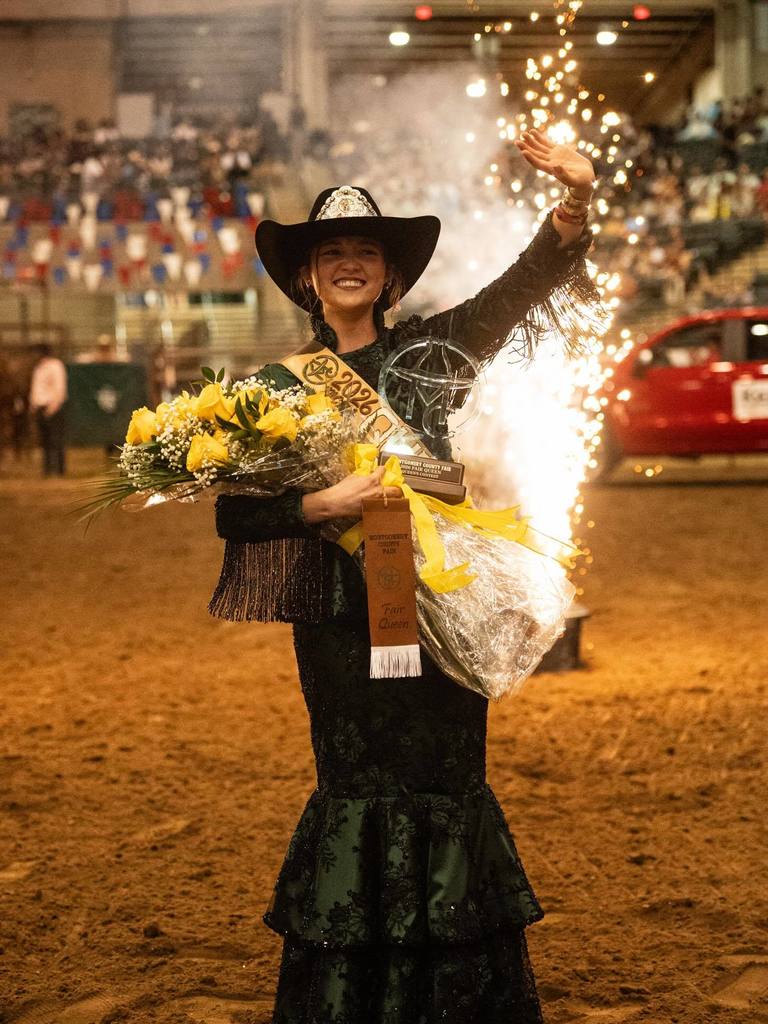 Montgomery County Fair Queen Delaney Miller waves as fireworks shoot off behind her.