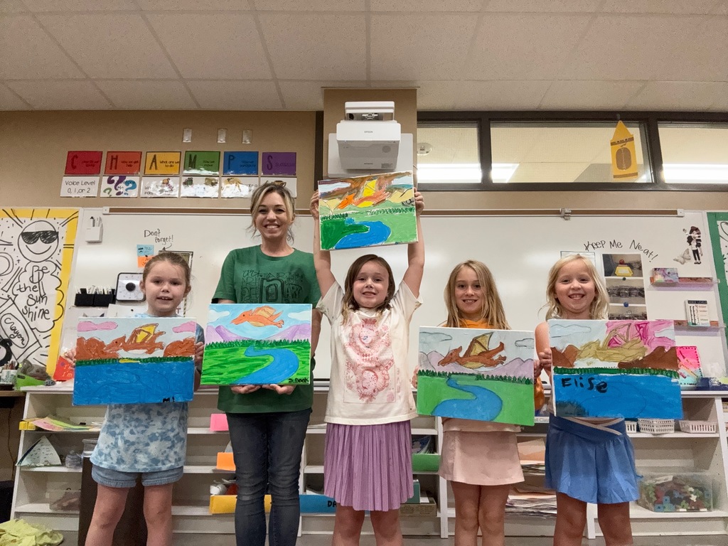 kids and teacher holding their artwork up together