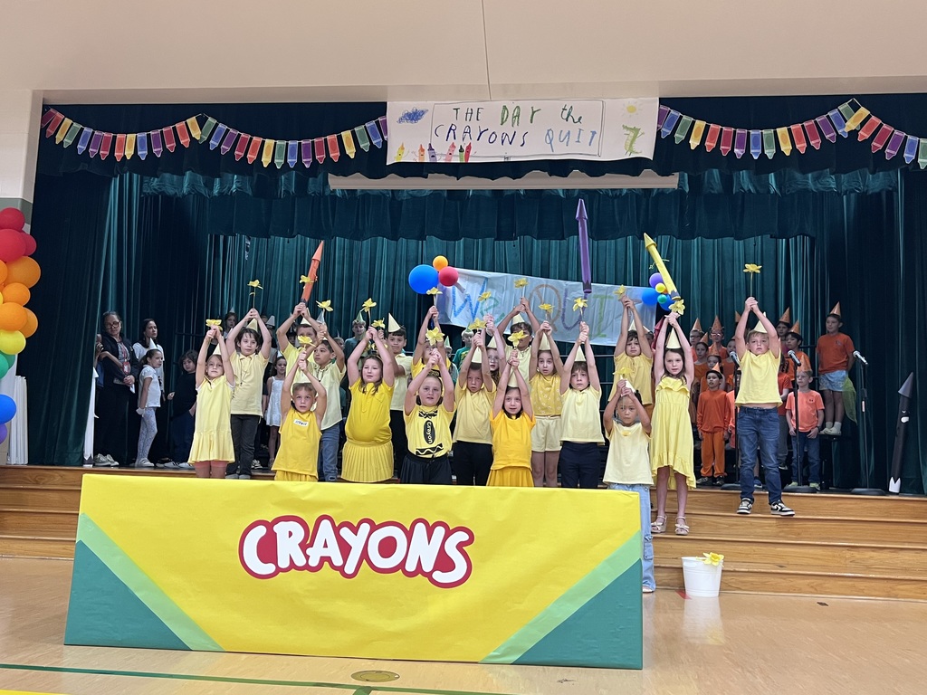 class of kids dressed in yellow holding up yellow flowers