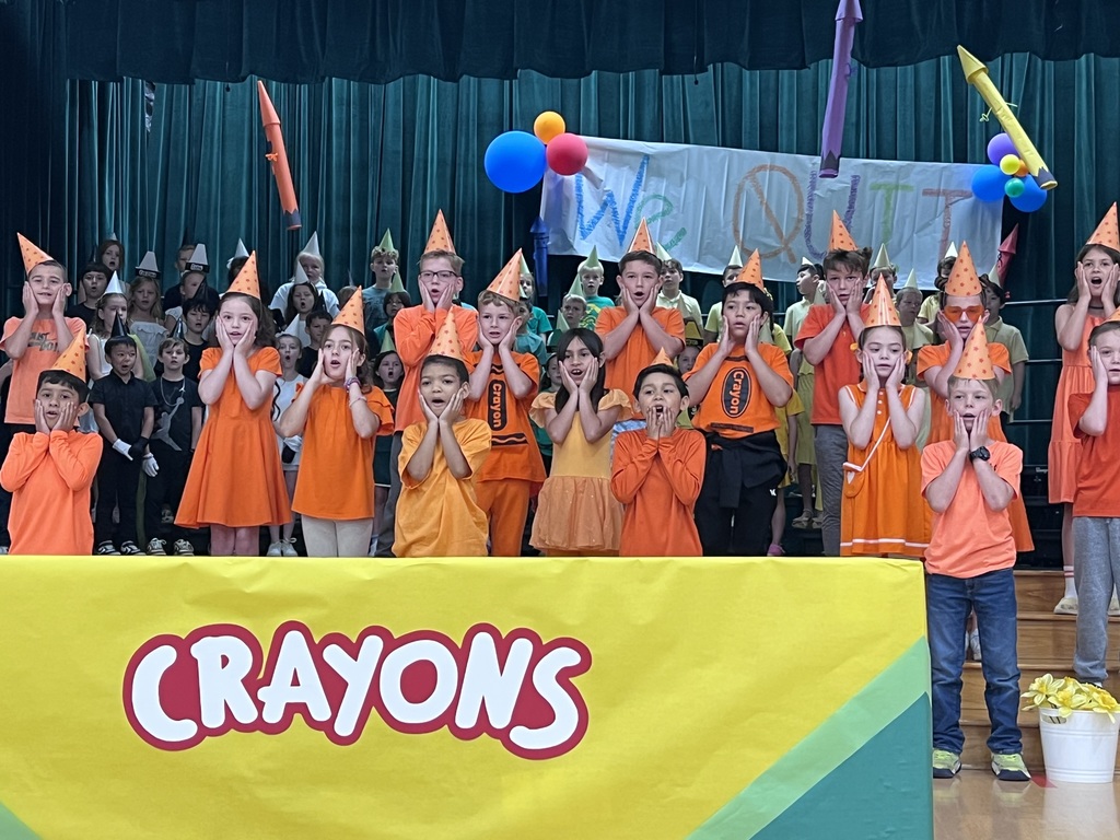 class of kids dressed in orange with hands on face in a surprised manner