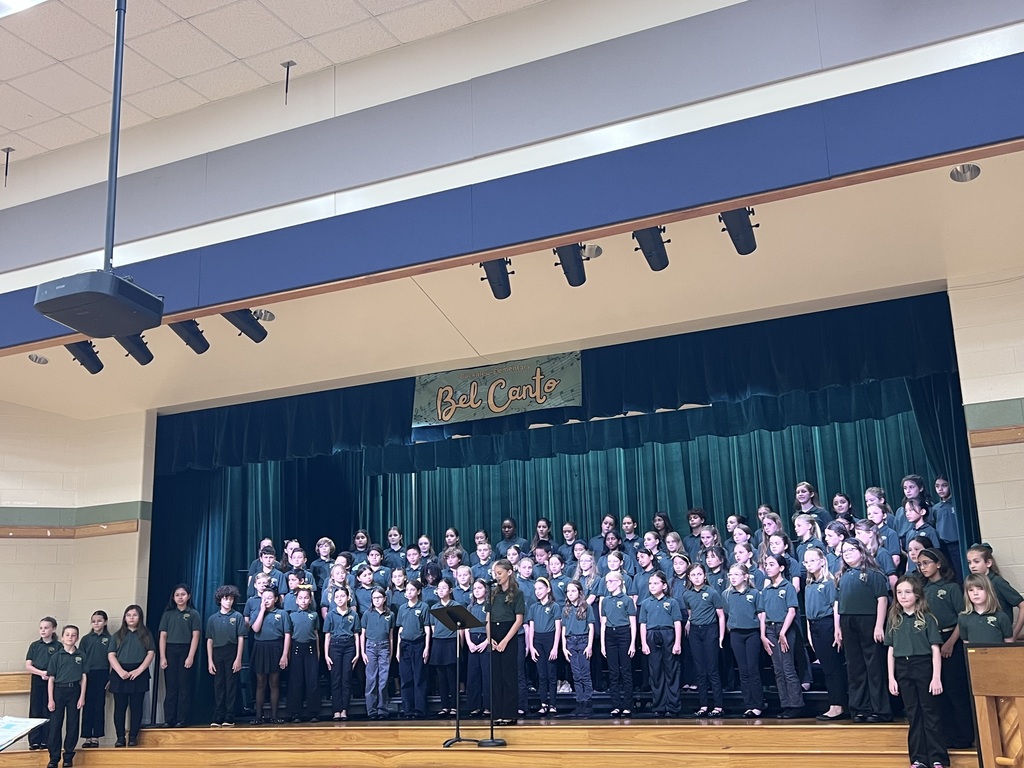 choir standing on stage with bel canto sign