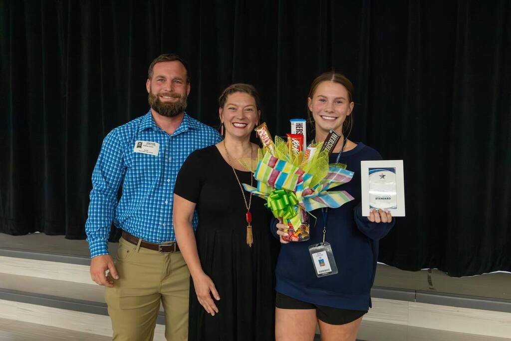 Student holding award plaque and candy bouquet joined by family.