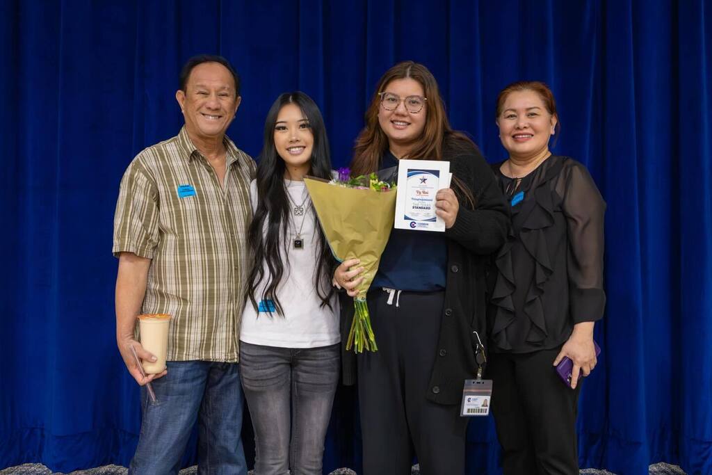 Staff member holding award plaque and flowers joined by family.