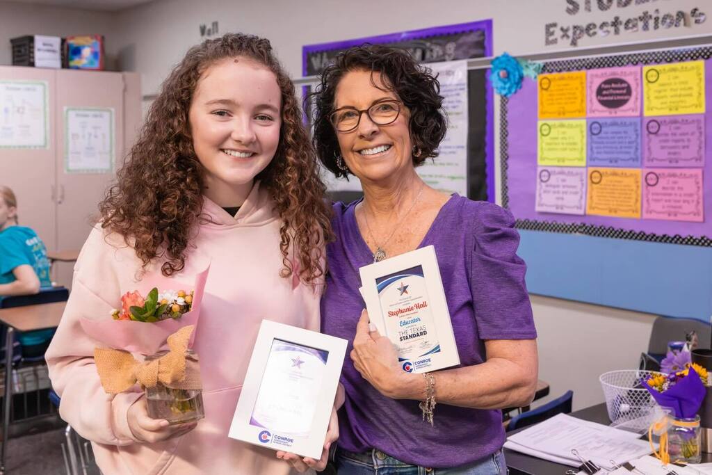 Student and teacher holding award plaques.