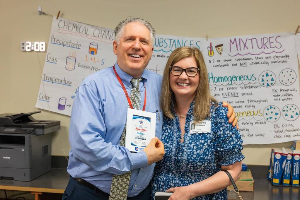 Educator holding award plaque with family.
