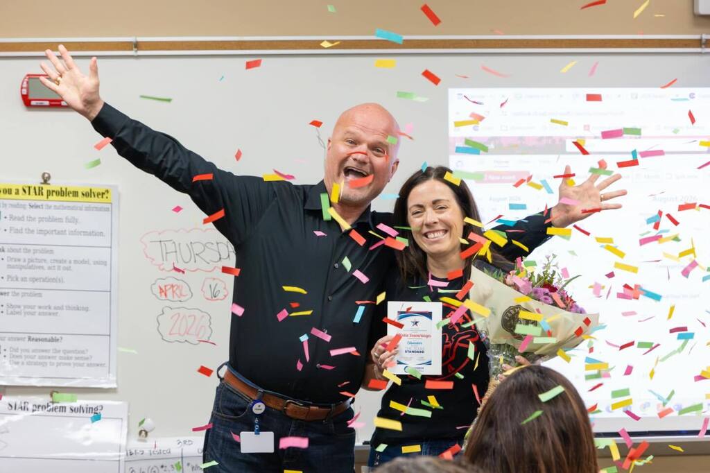 Teacher holds award plaque and flowers joined by Superintendent as confetti falls.