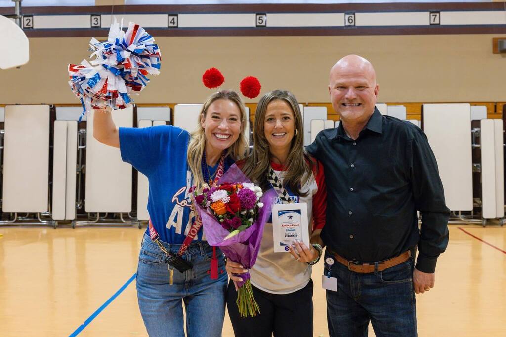 Staff member holds award plaque joined bv principal and Superintendent.