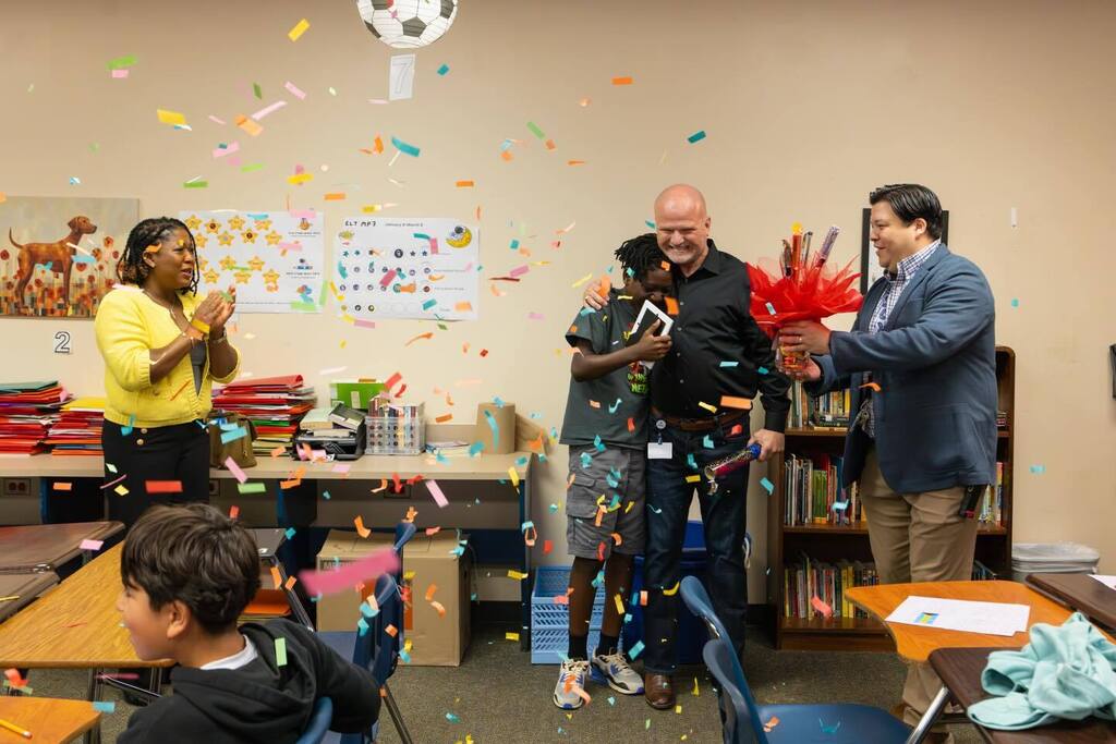 Student hugs Superintendent afte receiving award as confetti falls.