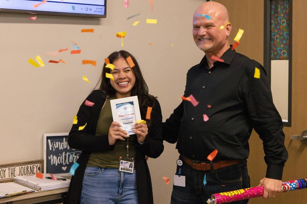 Staff member smiles as Superintendent pops confetti.