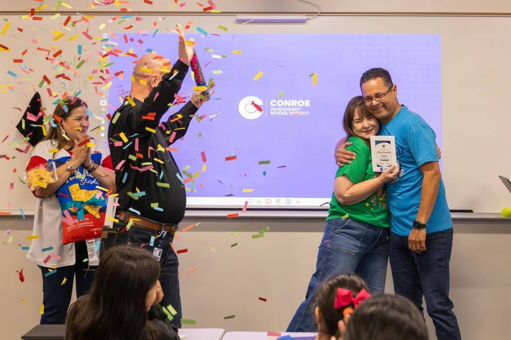 Teacher hugs administrator as confetti falls.