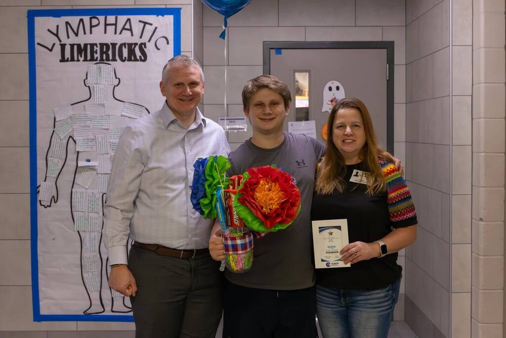 Student holding gifts joined by family.