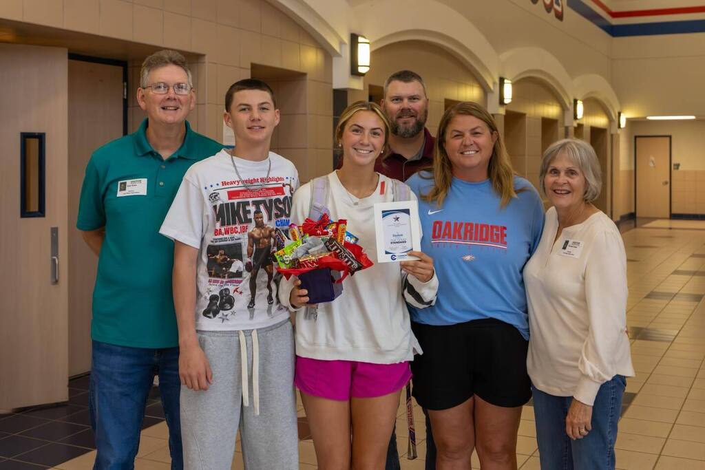 Student holding award plaque and candy bouquet joined by family.