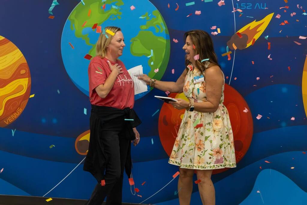 Staff member given award by Board President as confetti falls.