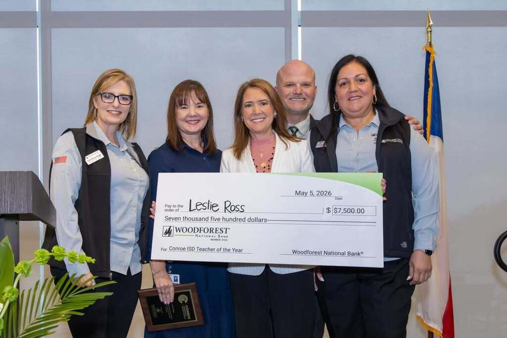 Teacher holding a giant check joined by administrators and sponsors.