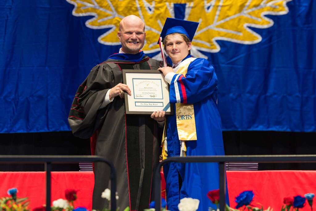 Valedictorian and superintendent with plaque.