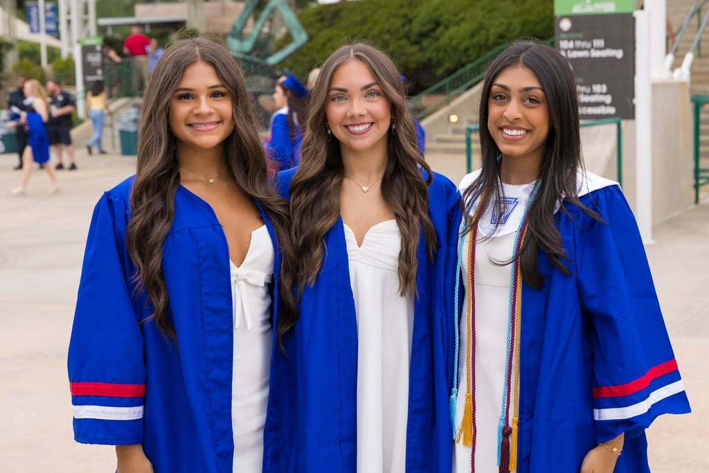 Three graduates in blue robes.