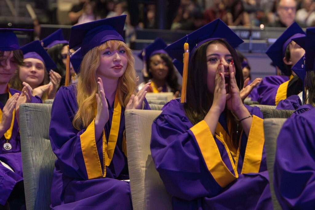 Two female students cheer at graduation ceremony.
