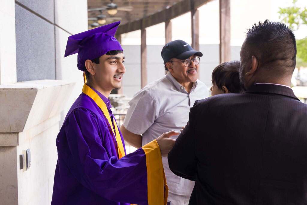 Graduate in purple robe talks to family.