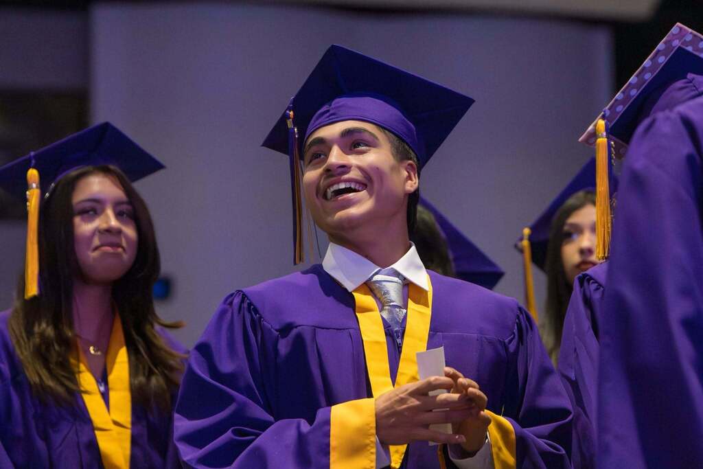 Graduate in purple robe smiles.
