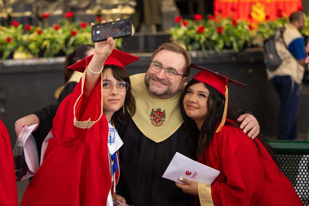 Teacher takes selfie with two graduates.