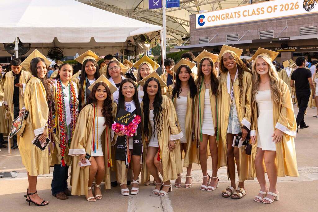 Twelve females students in dresses and gold caps and gowns.
